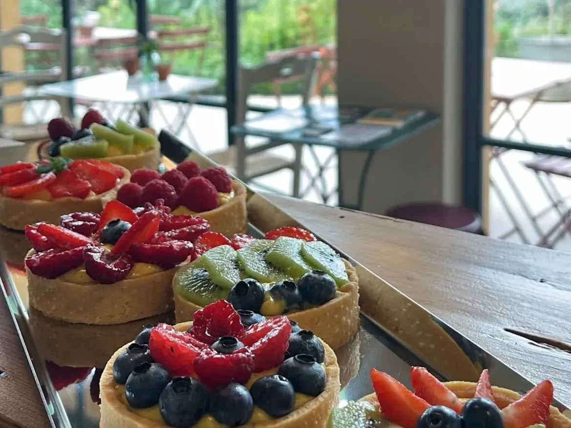 Una crostatina al mandarino lucida su un bancone di legno, la vetrina dei dolci illuminata alle spalle