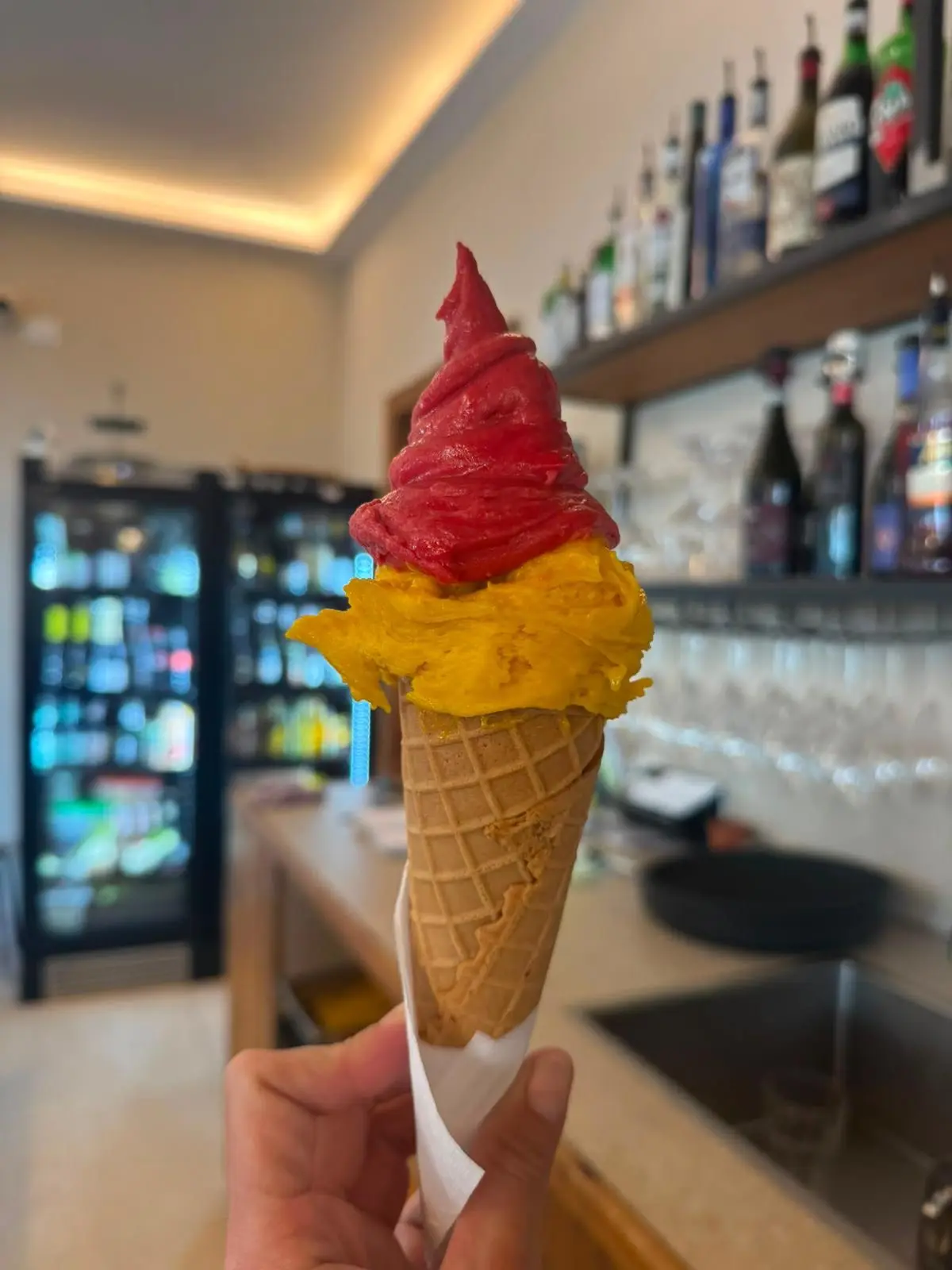 Un cono con gelato artigianale al mango e lampone davanti al banco bar di Hortus